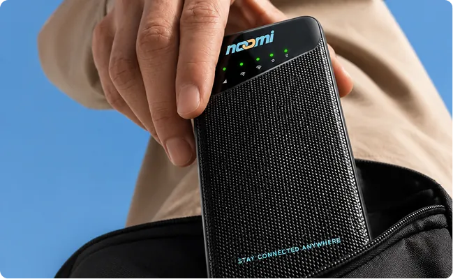 A hand slipping the pocket-size Noomi device into the front pouch of a bag